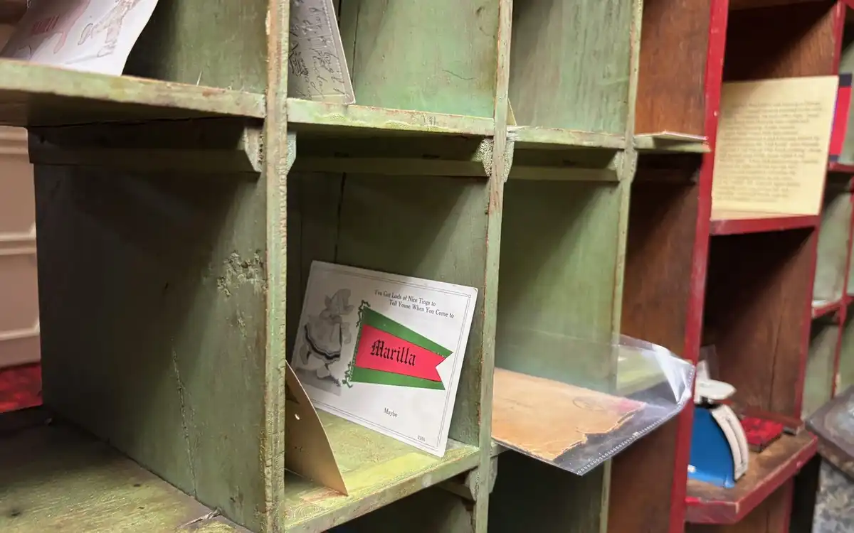 Wooden mail sorting slots, painted green and red, with a few letters left in them.