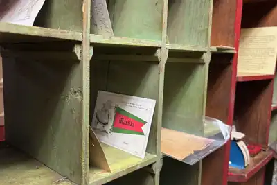 Wooden mail sorting slots, painted green and red, with a few letters left in them.