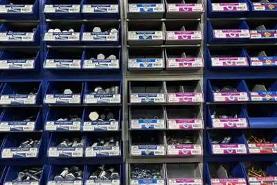 A wall of small blue drawers, each labelled and holding a different size of bolt or screw.